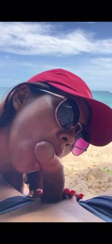 Asian babe giving a brown boy some mouth on the beach