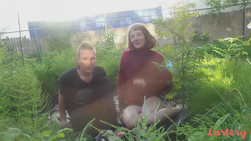 Joy & Mark touch grass, while touching each other.
